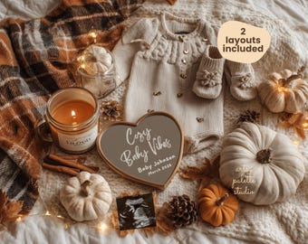 Könnte beinhalten: Herbstliche Babyankündigung mit cremefarbenem Baby-Outfit, Babyschuhen und kleinen Kürbissen. Eine brennende Kerze, Zimtstangen und ein herzförmiges Schild mit dem Text "Cozy Baby Vibes" sind ebenfalls im Bild zu sehen.