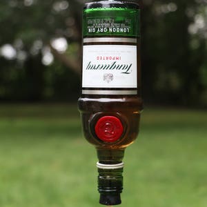 May include: A repurposed Tanqueray London Dry Gin bottle, inverted and fitted with a red stopper and a clear tube. The bottle is suspended by a metal hook. The label reads "Tanqueray Imported London Dry Gin".