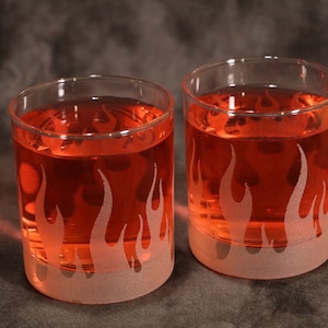 Op de afbeelding: Twee heldere glazen met een gematteerd vlammenontwerp. De glazen zijn gevuld met een rode vloeistof.