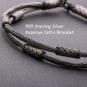 May include: A 999 sterling silver Kazaziye Celtic bracelet featuring a double-strand design with intricate woven metal patterns and cylindrical accents. The text 999 Sterling Silver Kazaziye Celtic Bracelet is clearly visible on the image.