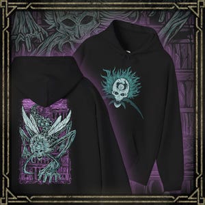 May include: Black hoodie with a detailed graphic of a skull with teal hair and an eye on the forehead. The back of the hoodie features a detailed illustration of a creature with insect-like wings and a skeletal face, in shades of teal and purple.