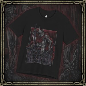 May include: Black t-shirt with a detailed illustration of a knight holding a sword, surrounded by other swords. The knight is in armour with a red cape. The design is set against a red background.