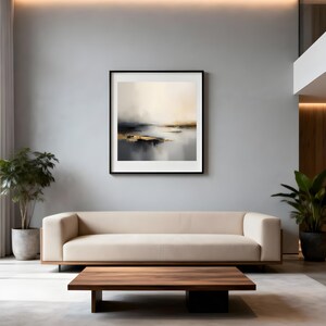 Puede incluir: Una pintura abstracta de paisaje en un marco negro cuelga sobre un sof&aacute; beige. La obra de arte presenta una paleta de colores apagados de beige, gris y dorado, que representa un sereno paisaje acu&aacute;tico. Una mesa de centro de madera oscura se encuentra frente al sof&aacute;.