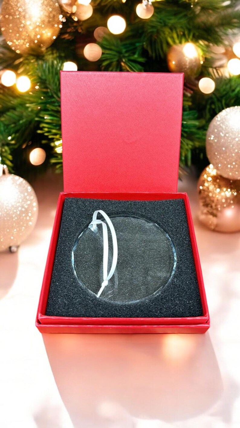 May include: A clear glass ornament with a white string hanger, in a red box with black foam padding.