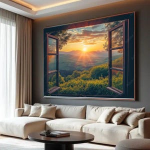 May include: Large framed wall art depicting an open window overlooking a vibrant sunset over a mountain range. The window frame is dark brown, and the landscape features lush green foliage and a bright orange sun. The artwork is displayed above a cream-colored sectional sofa.
