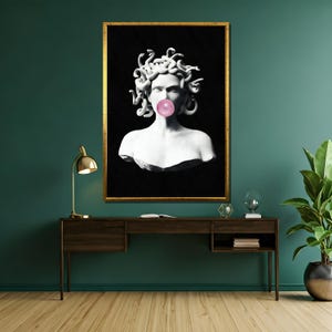 Puede incluir: Una impresi&oacute;n en blanco y negro de un busto de m&aacute;rmol de Medusa con serpientes para el cabello, soplando una burbuja rosa. El busto est&aacute; enmarcado en un marco dorado.