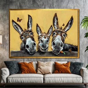 Puede incluir: Una pintura de tres burros con expresiones divertidas. Los burros son marrones y blancos y tienen orejas largas. Están mirando al espectador con la boca abierta. Hay mariposas y una zanahoria en la pintura.