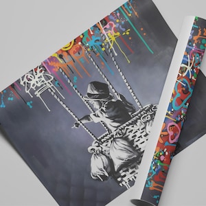 May include: A black and white painting of a child on a swing, with colourful paint splatters in the background. The child is wearing a hooded jacket and holding onto the ropes of the swing. The swing is suspended from a hot air balloon.
