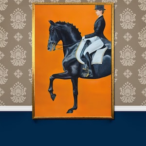 May include: A framed equestrian painting featuring a black horse in a dressage pose with a rider in formal attire. The artwork has a gold frame and an orange background. The painting is set against a patterned wallpaper and a blue wall.