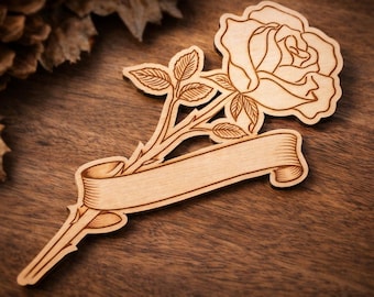 Könnte beinhalten: Eine Holzrose mit Stiel, Blättern und einer Schriftrolle für Text. Die Rose und die Blätter sind detailliert, und das Holz hat einen hellbraunen Farbton. Die Schriftrolle ist leer und kann personalisiert werden. Auf einer Holzoberfläche.