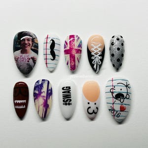 Könnte beinhalten: Zehn mandelförmige Nageldesigns. Die Designs zeigen ein Foto, einen Schnurrbart, eine britische Flagge, ein Korsett, silbernen Glitzer mit schwarzen Punkten, ein Cartoon-Gesicht, eine Palme, das Wort "SWAG", ein Gesicht mit der Zahl 3 und ein Cartoon-Gesicht mit dem Jahr 2016.
