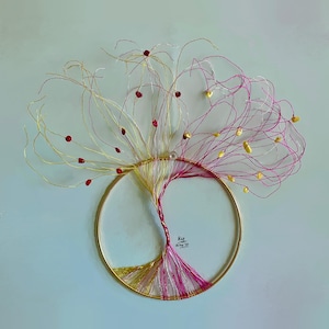 May include: A wire sculpture of a tree with red and gold wire branches and beads. The tree is mounted on a gold metal hoop. The text "Red 21 Sep '21" is written on the tree trunk.