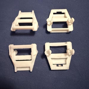 May include: Four white plastic 3D printed objects with a rectangular shape and a grid pattern. The objects have a slightly raised edge around the perimeter.