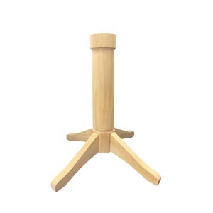 May include: A light-colored wooden table base with a three-legged design. The base has a central column and a circular top, suitable for supporting a tabletop. The wood grain is visible.