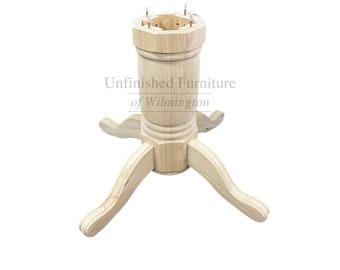 May include: Unfinished wooden table base with three curved legs and a central column. The column has a decorative, turned design and a hexagonal top with holes for attachment. The text "Unfinished Furniture of Wilmington" is visible.