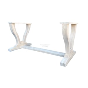 May include: Unfinished white wood table base with a trestle design. The base has two legs on each side, with a curved top and a square bottom. The base is made of solid wood and is ready to be stained or painted.