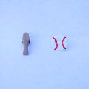 May include: A brown wooden baseball bat and a white baseball with red stitching.