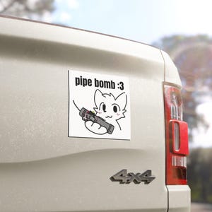 Könnte beinhalten: Quadratischer weißer Aufkleber mit einer Cartoon-Katze, die eine Rohrbombe hält, mit dem Text "pipe bomb :3" in Schwarz. Der Aufkleber befindet sich auf der Rückseite eines weißen Fahrzeugs.