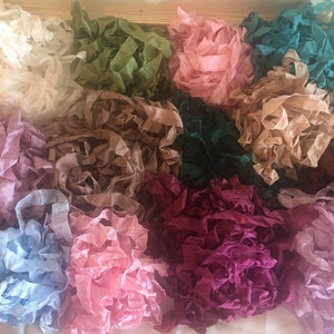 May include: Assortment of 10 different colors of silk ribbon, including teal, pink, brown, purple, light blue, and green. The ribbon is arranged in a pile on a white surface.