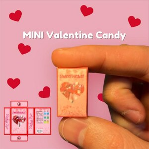 May include: A miniature box of Valentine's Day candy with a pink and white heart design. The box says "Sweetheart" and "Valentine's Day" on the front.