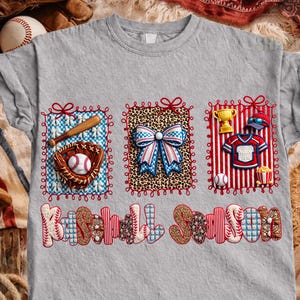 Puede incluir: Una camiseta gris con temática de béisbol con tres diseños enmarcados. Los diseños incluyen un guante y un bate de béisbol, un lazo y un uniforme de béisbol. Las palabras "Baseball Season" están impresas en la parte inferior.