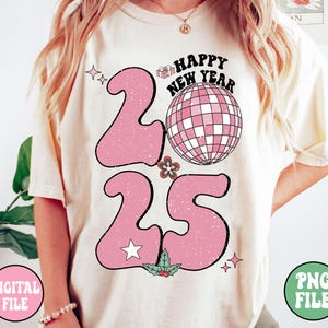 K&ouml;nnte beinhalten: Ein wei&szlig;es T-Shirt mit einem pinkfarbenen Grafikdesign des Jahres 2025. Die Zahlen sind im Retro-Stil mit einer Discokugel und dem Text "Happy New Year" gestaltet.