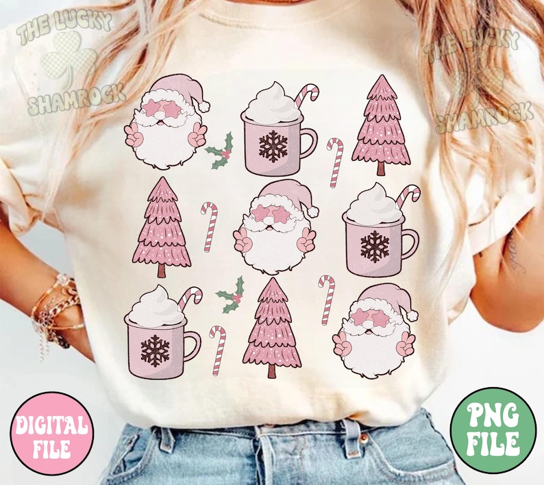 K&ouml;nnte beinhalten: Ein wei&szlig;es T-Shirt mit einem rosa-wei&szlig;en Weihnachtsmotiv. Das Design zeigt den Weihnachtsmann, Weihnachtsb&auml;ume und Tassen mit hei&szlig;er Schokolade mit Schlagsahne.