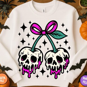 May include: White sweatshirt featuring a graphic of two cherries with skull faces, dripping pink 'juice', and a pink bow. The design includes black star accents. A unique and spooky design for Halloween.