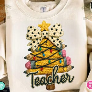 May include: Cream-colored sweatshirt featuring a Christmas tree design made of pencils, a bow, and a star. The pencils are yellow with pink erasers and are decorated with colorful lights. The word "Teacher" is written in a script font.