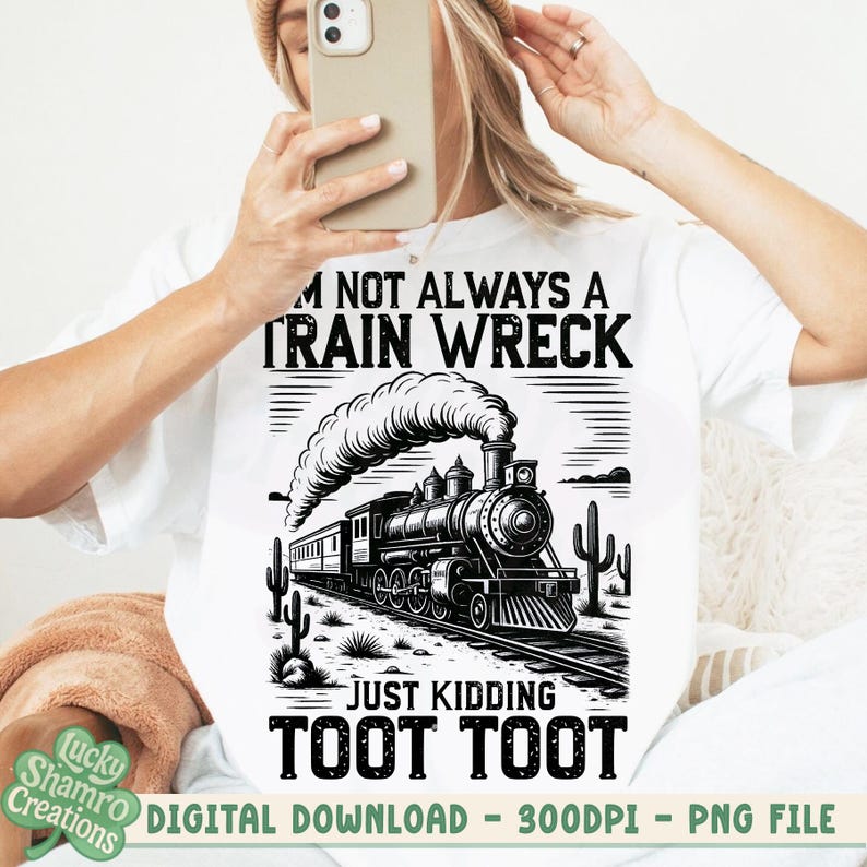 K&ouml;nnte beinhalten: Wei&szlig;es T-Shirt mit einer schwarz-wei&szlig;en Grafik einer alten Dampflokomotive. Der Text lautet: "I'm not always a train wreck, just kidding, toot toot." Das Design beinhaltet Kakteen und eine W&uuml;stenlandschaft.