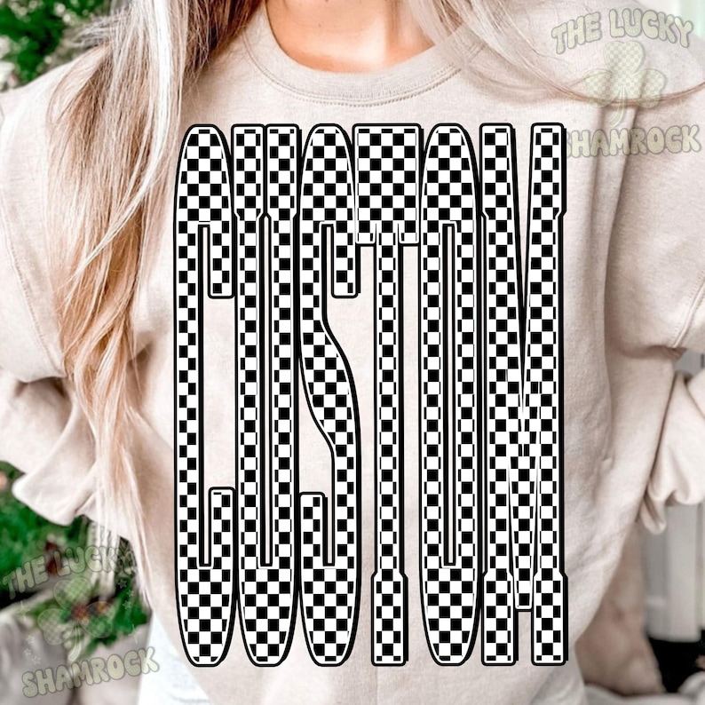 May include: A beige crewneck sweatshirt featuring a large graphic on the front. The graphic consists of the word CUSTOM written in a tall, bold, sans-serif font filled with a black and white checkerboard pattern. The text is centered on the chest.