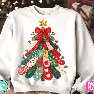 May include: White sweatshirt featuring a colorful Christmas tree design. The tree is made of various textured, stitched elements in red, green, yellow, and blue, topped with a gold star and red bow. The design includes hearts and other festive details.