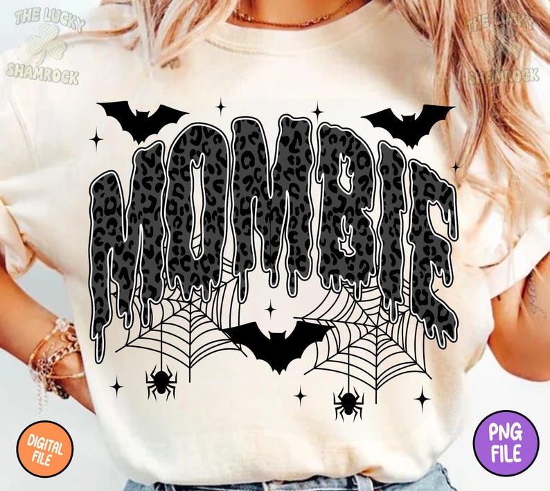 May include: Cream-colored t-shirt with the word "MOMBIE" in a dripping, leopard-print design. The design includes bats, spiderwebs, spiders, and stars, creating a Halloween theme. The shirt also has the text "DIGITAL FILE" and "PNG FILE".