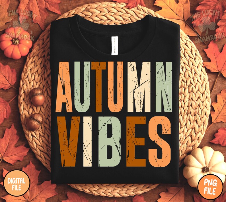 May include: Black t-shirt with the words "AUTUMN VIBES" in orange, green, and white distressed lettering. The shirt is on a woven mat surrounded by fall leaves, pumpkins, and acorns. The shirt is a digital file.