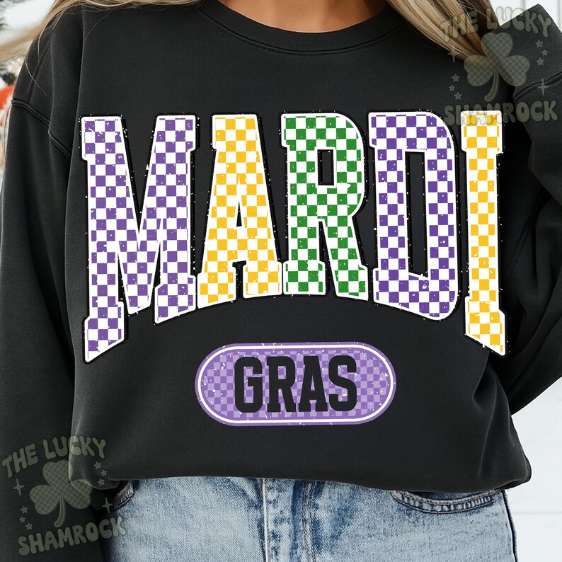 May include: Black sweatshirt featuring the text "MARDI GRAS" in large, checkered letters. The letters are purple, yellow, and green, with a matching checkered oval below that says "GRAS". A festive design for celebrations.