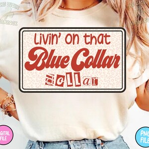 Puede incluir: Camiseta color crema con un gr&aacute;fico rectangular. El gr&aacute;fico presenta el texto "Livin' on that Blue Collar dollar" en una fuente retro, con un fondo de estampado de leopardo. La camiseta tiene mangas cortas.
