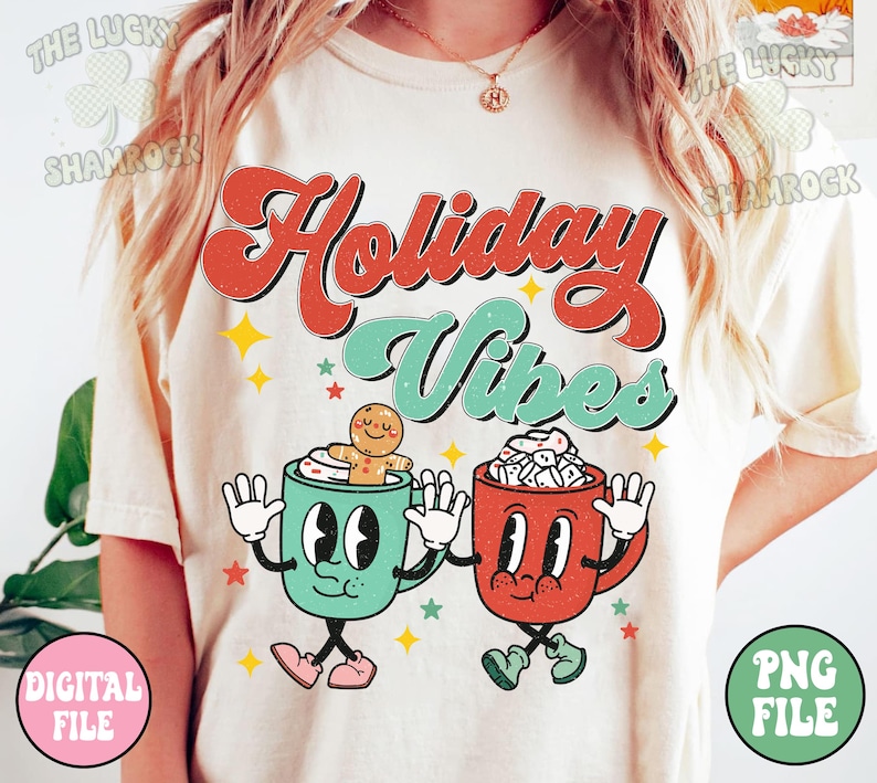 May include: Cream-colored t-shirt with the words "Holiday Vibes" in red and teal retro font. Two cartoon mugs with faces and arms are featured below the text, one with a gingerbread man and the other with marshmallows. Stars and the words "Digital File" and "PNG File" are also visible.