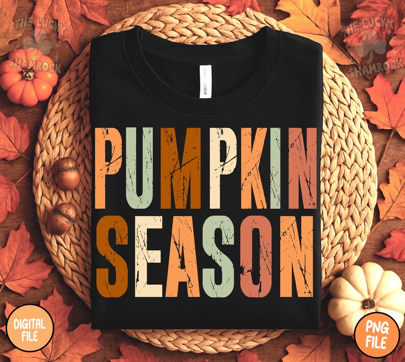 May include: Black t-shirt with the words "PUMPKIN SEASON" in large, distressed, colorful letters. The shirt is surrounded by fall leaves, pumpkins, and acorns, creating a seasonal autumn theme.