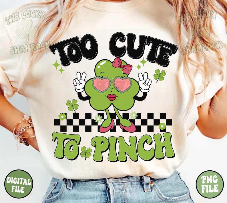 Peut inclure: Un t-shirt blanc avec un tr&egrave;fle vert portant des lunettes de soleil et un n&oelig;ud rose. Le tr&egrave;fle l&egrave;ve deux doigts en signe de paix. Le texte "Too Cute To Pinch" est &eacute;crit en lettres vertes et noires.