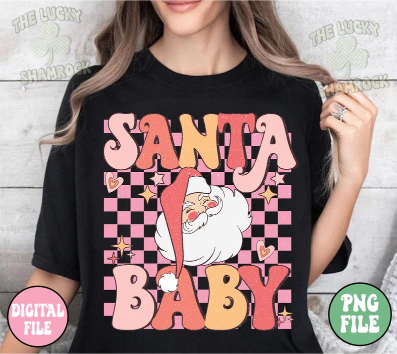 May include: Black t-shirt with a retro design featuring the words "SANTA BABY" in pink, orange, and peach. Santa Claus is in the center, with a pink and black checkered background, hearts, and stars.