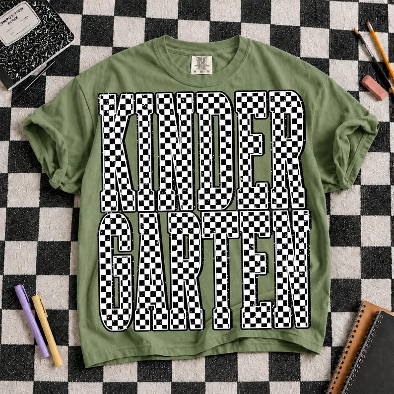 K&ouml;nnte beinhalten: Ein olivgr&uuml;nes Kurzarm-T-Shirt mit dem Wort KINDERGARTEN, das in gro&szlig;en, fetten, schwarz-wei&szlig; karierten Blockbuchstaben in der Mitte aufgedruckt ist. Das T-Shirt hat einen Rundhalsausschnitt und eine Standardpassform mit einem sichtbaren Markenetikett.