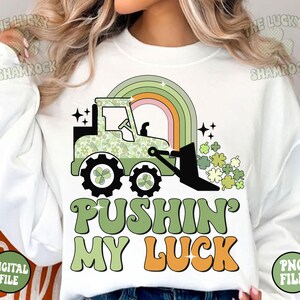 Peut inclure: Un sweat-shirt blanc avec un tracteur vert et un arc-en-ciel. Le texte "Pushin' My Luck" est &eacute;crit en lettres vertes et orange.