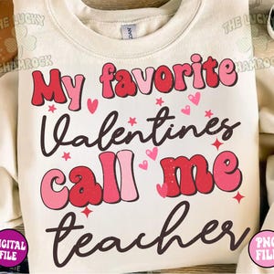 May include: A white sweatshirt with the text "My favorite Valentines call me teacher" in pink and red letters with a distressed look. The text is surrounded by small hearts and stars.