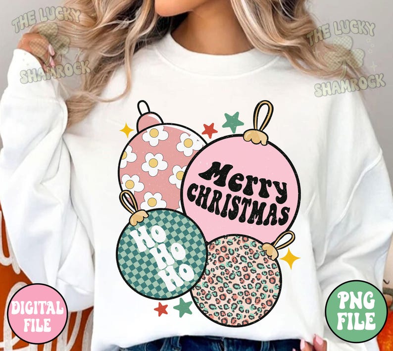 May include: A white sweatshirt featuring a graphic of four Christmas ornaments in pink, green, and leopard print. The ornaments have the text "Merry Christmas" and "Ho Ho Ho". The design includes stars and daisy patterns.