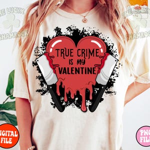 May include: A white t-shirt with a red dripping heart and two black knives. The heart has the text "True Crime is my Valentine" on it.