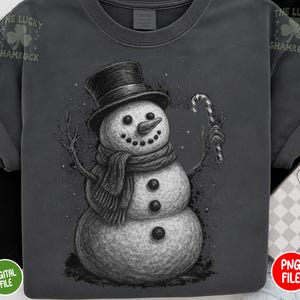 May include: Dark gray t-shirt featuring a detailed illustration of a snowman wearing a top hat and scarf, holding a candy cane. The snowman has a carrot nose and button eyes. The text "THE LUCKY SHAMROCK" is printed on the top left and right.