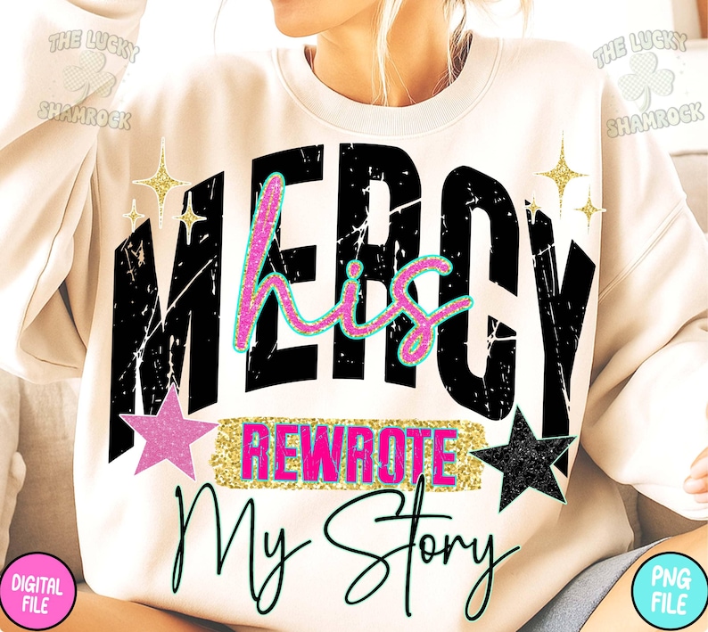 Puede incluir: Sudadera crema con las palabras "MERCY his REWROTE My Story" en letras negras, rosas y doradas con purpurina. El dise&ntilde;o incluye estrellas y una fuente desgastada. El logotipo de Lucky Shamrock es visible.