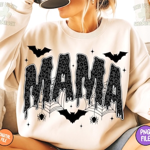 May include: Cream-colored sweatshirt with the word "MAMA" in a dripping, leopard-print design. The design includes bats, spiderwebs, spiders, and stars, creating a Halloween theme. The sweatshirt is a digital file.