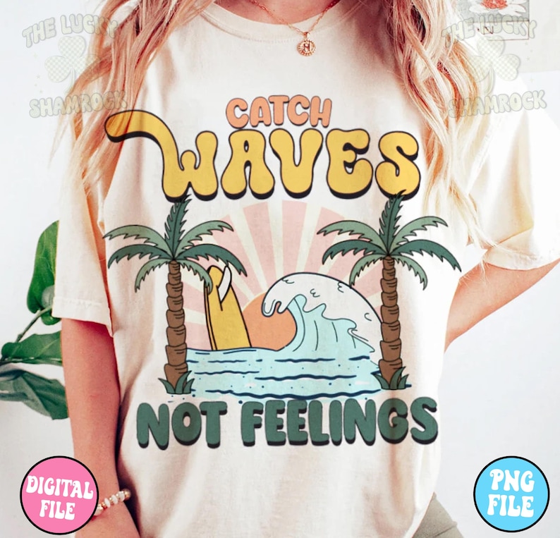 May include: A white t-shirt with a graphic design of a surfboard, palm trees, and a wave. The text "Catch Waves Not Feelings" is printed in green and yellow letters.