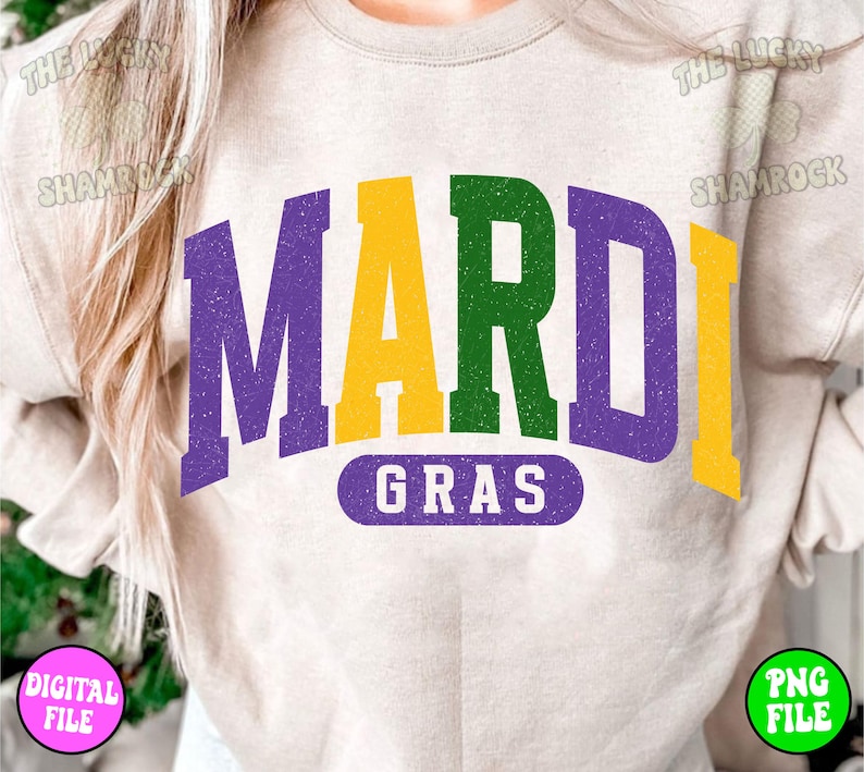 Puede incluir: Una sudadera beige claro con el texto "Mardi Gras" en letras moradas, amarillas y verdes. Las letras est&aacute;n en una fuente de estilo vintage con un aspecto desgastado.